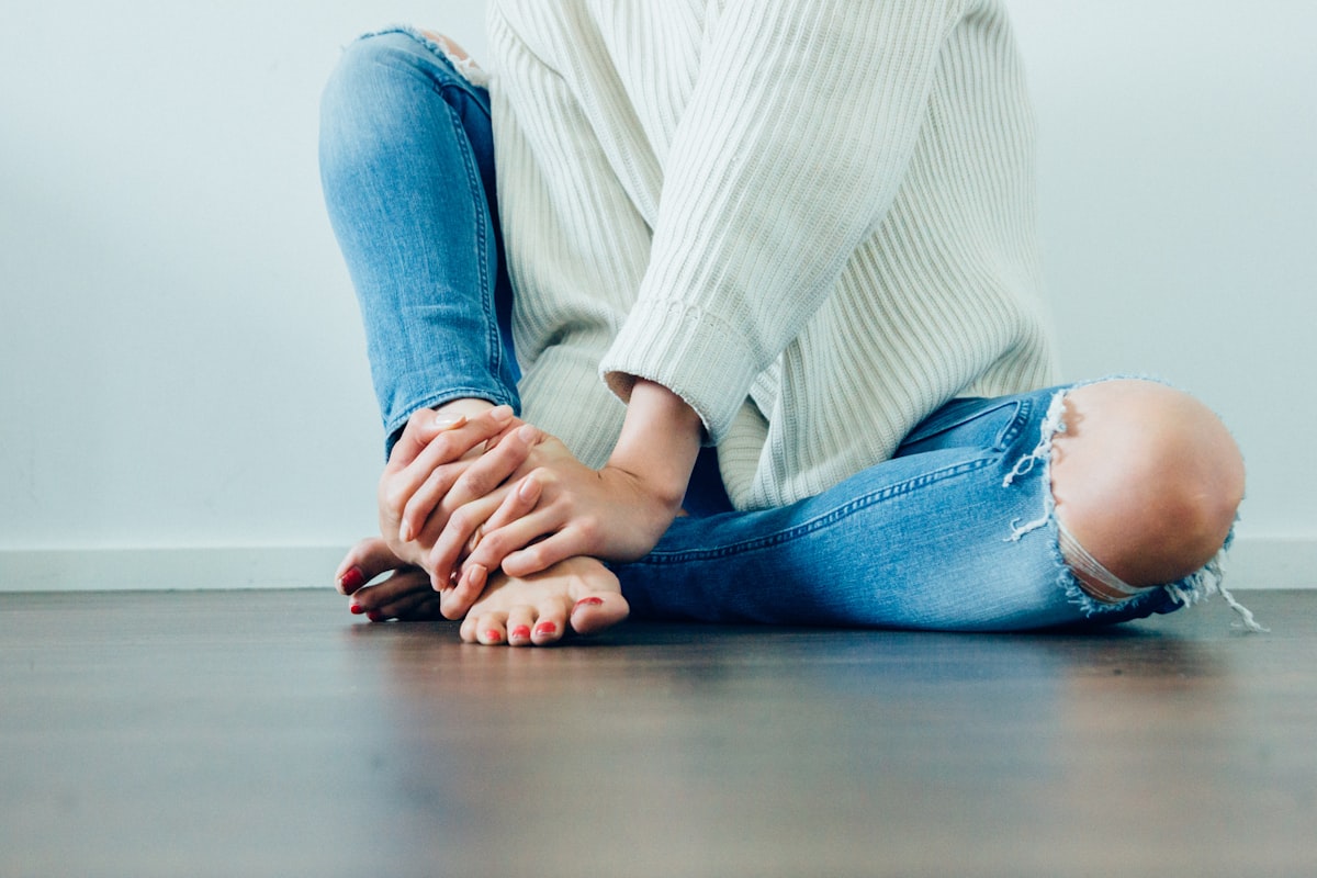 Person sitting and holding their heel in discomfort