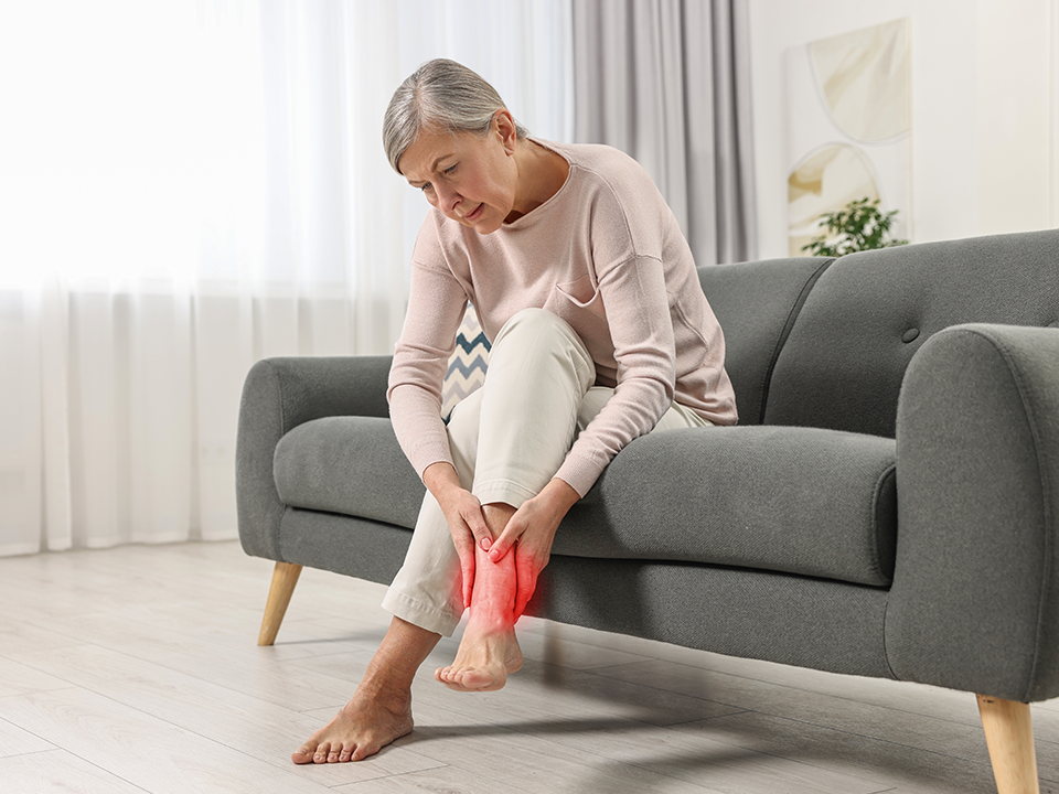 Woman sitting on a couch holding her foot in pain